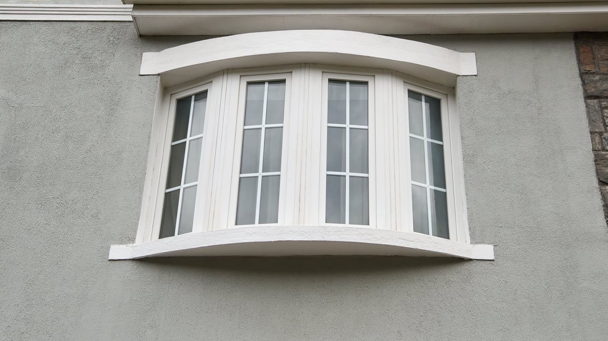 Four-panel curved white bay window on a stucco exterior wall